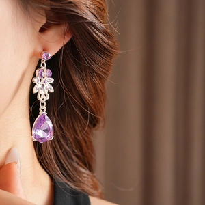 Close-up of vintage silver earrings with purple crystals and pear-shaped drop pendant