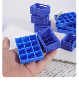 Close-up of miniature blue plastic storage crates and pallet models held in hand