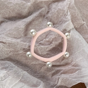 Detailed close-up of a pink elastic hair tie featuring six elegant white faux pearls