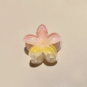 Macro view of gradient pink and yellow plumeria hair claw clip with pearlescent glitter finish