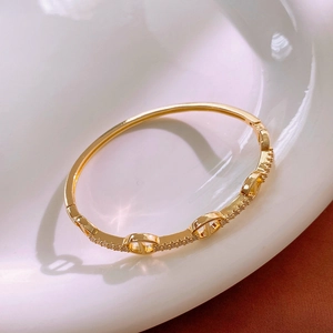 Macro view of gold plated pig nose bracelet with micro-paved zircons on white ceramic
