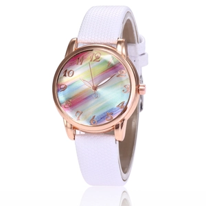Rose gold watch with rainbow striped dial and white textured strap at 45-degree angle