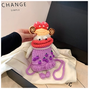 Detail of crochet sausage mouth doll bag with purple dress and pink bow inside gift box