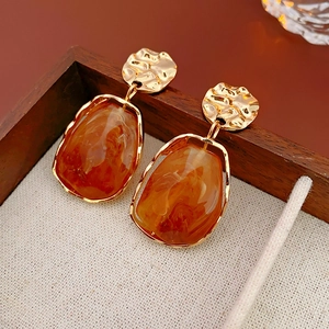Close-up of vintage irregular golden earrings with amber resin inserts on wooden frame