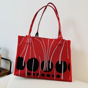 Close-up of red knitted tote bag with black dots and grey lines pattern texture