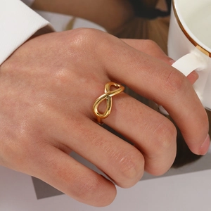 Minimalist gold infinity stainless steel ring worn on hand with white coffee cup