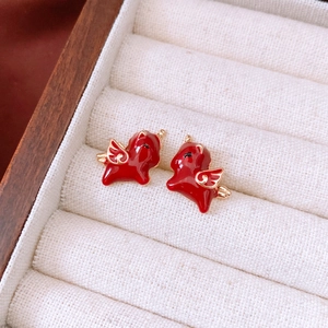Detailed view of 18k gold plated flying animal earrings with red enamel on velvet