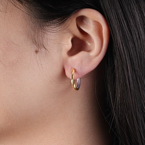 Detail of two-tone gold and silver titanium steel hoop earrings worn on female ear