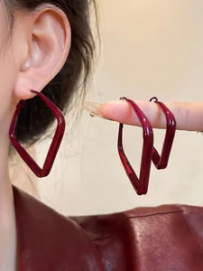 Detail of square oversized earrings in deep burgundy red lacquer finish for a retro look