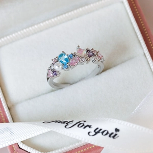 Macro detail of silver heart ring with colorful zircon gems and pearl in a gift box