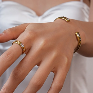 Close-up of gold stainless steel bangle and ring set with teardrop zircon on a model