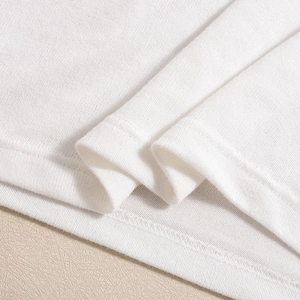 Macro detail of high-density stitching and hemline on a white knitted backless dress