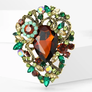 Detailed close-up of retro gold-tone brooch with colorful rhinestones and amber stone
