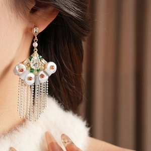 Close-up of vintage gold fan-shaped earrings with pearls, rhinestones and metal tassels