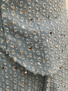 Vue détaillée du tissu denim avec texture usée et embellissements de paillettes argentées