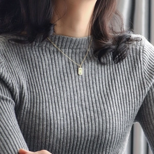 Elegant gold plated necklace with rectangular green stone pendant shown on a model