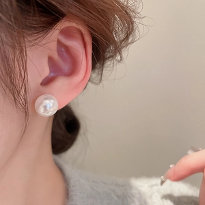 Close-up of a high-luster white pearl stud earring on model for elegant fashion styling