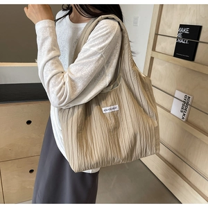 Große beige Tragetasche mit plissiertem Stoff und Seitenetikett in Lifestyle-Ansicht
