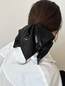 Close-up of a large black satin bow scrunchie on a ponytail with premium glossy texture