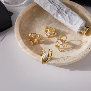 Detalle de cuatro anillos dorados de circón presentados en una elegante bandeja de mármol
