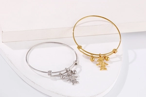 Détail de bracelets réglables en acier titane avec pendentifs garçon en finitions or et argent