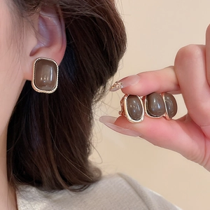 Detail of vintage square resin stud earrings with golden textured metal spiral frames