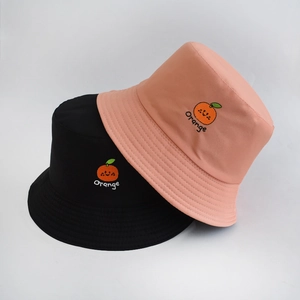 Detail of embroidered orange fruit patterns on black and pink cotton bucket hats