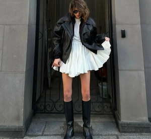 Photo street style d'une jupe plissée blanche taille haute et veste en cuir noir