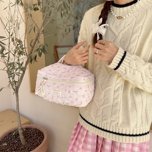 Pink quilted makeup bag with bear patterns carried by a model in a home setting