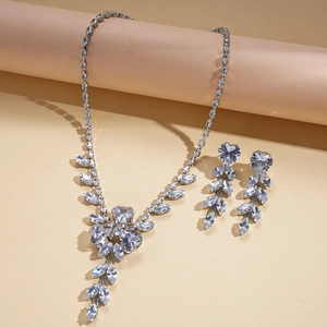 Elegant silver jewelry set with zircon heart and leaf pendants on warm background