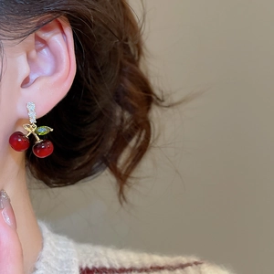Gros plan sur la boucle d'oreille cerise rouge avec feuille en pierre verte