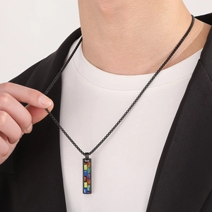 Close-up of a black dog tag necklace with rainbow geometric pattern on a male model