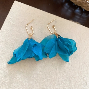 Detail view of blue chiffon fabric flower earrings with elegant gold metal hooks