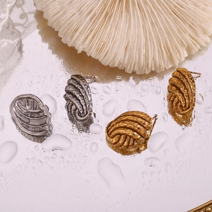 Detailed macro view of 18K gold and silver button stud earrings with spiral hammer texture