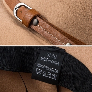 Detail view of brown felt hat with leather strap, silver buckle, and 100% polyester label