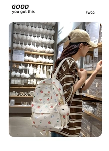 Close-up of cute strawberry and bunny pattern on white backpack with fuzzy pom-pom charm