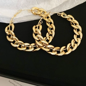 Close-up of gold chunky Cuban link hoop earrings featuring a high-polish metallic finish