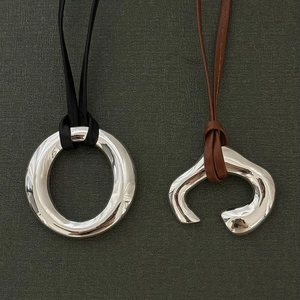 Close-up of minimalist silver round pendant necklaces with black and brown cords
