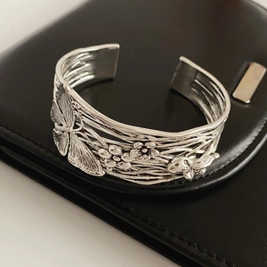 Detail of vintage silver open cuff bracelet with butterfly and floral carvings