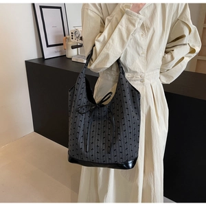 Detailed view of striped fabric tote bag with bow accent and leather trim on model