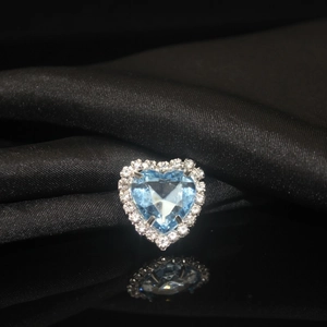 Macro shot of heart-shaped light blue crystal with white zircon border on black silk