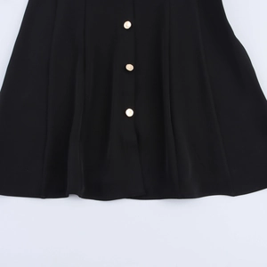 Detailed macro view of black sleeveless dress with gold buttons and soft pleated waist