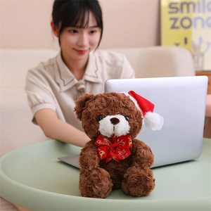 Brown plush teddy bear wearing a red Christmas hat and Merry Christmas ribbon bow