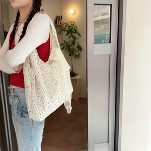 Detailed side profile of a cream floral canvas bag with elegant white lace ribbons