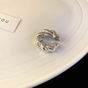 Gros plan détaillé d'une manchette d'oreille torsadée en argent sur une assiette blanche