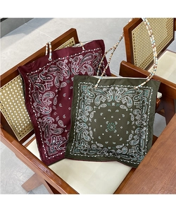 Detail of paisley print tote bags with beaded handles on a wooden chair