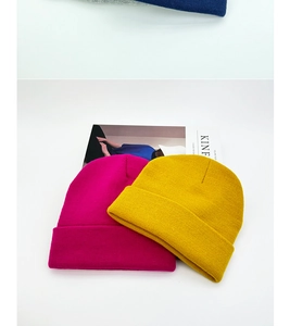 Close-up of mustard yellow and rose red double-layer knitted beanies with Kinfolk magazine