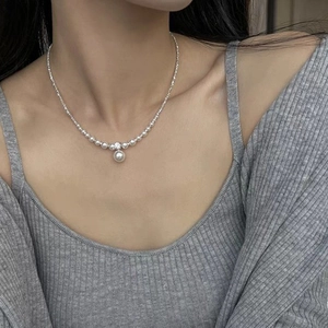 Elegant silver pearl necklace with zircon accents worn by a model on a gray knit sweater
