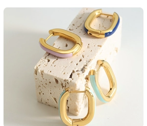 Macro view of multi-color enamel gold U-shaped earrings on stone background