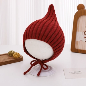Detail of red pointed knit baby hat showing ribbed texture and chin straps on mannequin